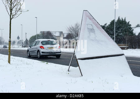 Chester UK. 18. Januar 2013. Ein Auto fährt Vergangenheit einen Schild Warnung vor rutschigen Straßenverhältnissen schneebedeckten. Stockfoto