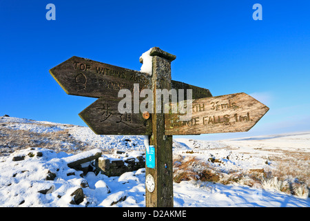 Pennine Way, Top Withens und Bronte fällt hölzerne Wegweiser auf Haworth Moor im Winter Schnee, Haworth, West Yorkshire, England, UK. Stockfoto