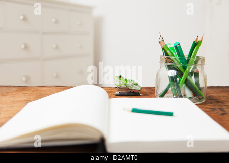 Glas mit Bleistift und Notizblock auf Tisch Stockfoto