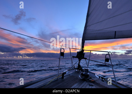 Squall weiter auf den Horizont bei Sonnenuntergang über den Bug eines Cruising Yacht offshore Segeln in den Sonnenuntergang von der Osterinsel zu Marquesas gesehen Stockfoto