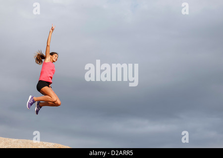 Frau springen vor Freude auf Findling Stockfoto
