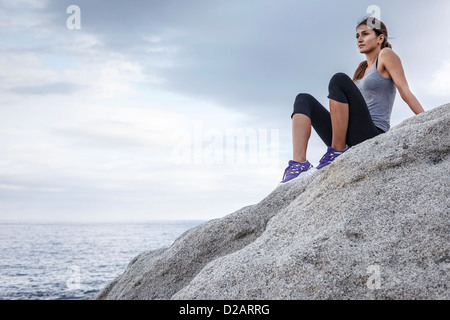 Frau auf Felsen mit Blick auf Meer Stockfoto