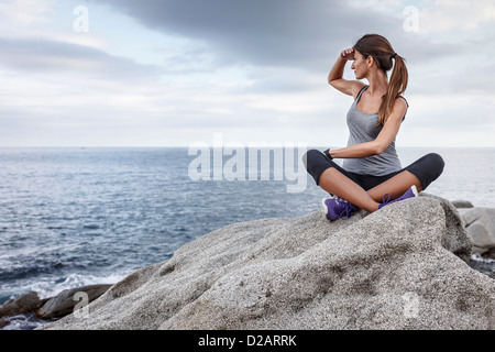 Frau mit Blick auf Ozean auf Findling Stockfoto
