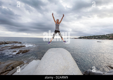 Frau springen vor Freude auf Findling Stockfoto