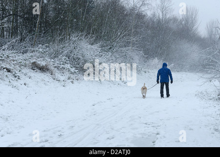 Ein Mann geht seinen Hund auf einer Schnee bedeckten Fußweg Stockfoto