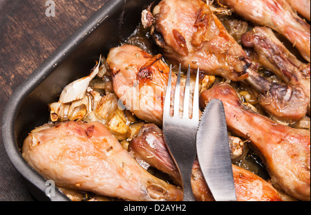 gebackene Hähnchenschenkel im Tray auf schwarzem Hintergrund aus Holz Stockfoto