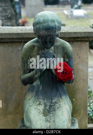 Freiburg, Deutschland, eine trauernde schwere Figur mit rote Rose auf dem Friedhof Stockfoto