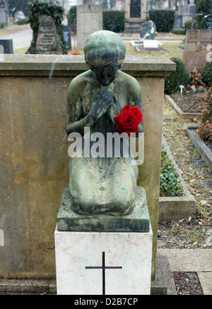 Freiburg, Deutschland, eine trauernde schwere Figur mit rote Rose auf dem Friedhof Stockfoto