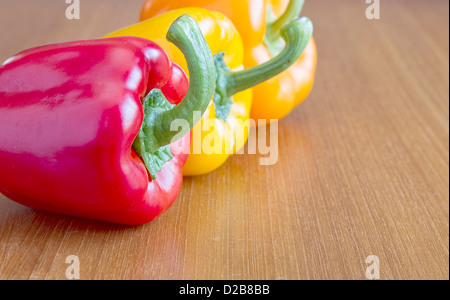 Rote, gelbe und orange Paprika auf Holztisch Stockfoto