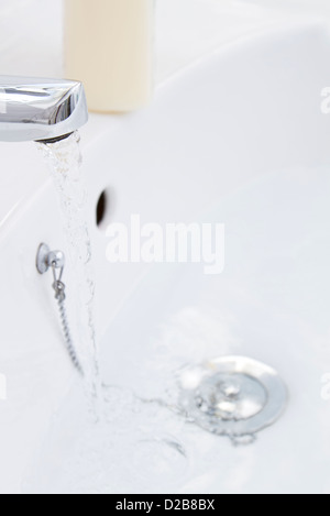 Wasser vom Hahn ins Waschbecken fließt Stockfoto