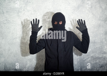 Das Konzept der Einbrecher, Dieb mit Sturmhaube gefangen vor der Betonwand Grunge zu fangen. Stockfoto