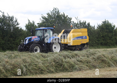 Herstellung von Heuballen in einem Feld in Essex Traktor Stockfoto