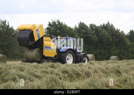 Herstellung von Heuballen in einem Feld in Essex Traktor Stockfoto