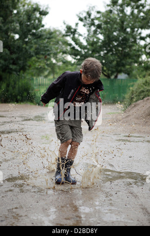 Glänzend, Deutschland, Dorfjunge herumspringen in einer Pfütze Stockfoto