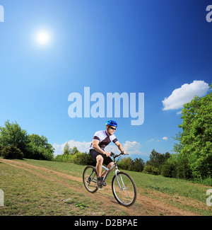 Männliche Radfahrer auf einem Mountainbike bergab an einem sonnigen Tag erschossen mit einem Tilt-Shift-Objektiv Stockfoto