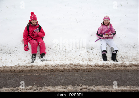 Junge Schulmädchen sitzen am Straßenrand nach einem schweren Sturz von Schnee ländliche Lage in Hampshire, England UK Stockfoto