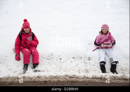 Junge Schulmädchen sitzen am Straßenrand nach einem schweren Sturz von Schnee ländliche Lage in Hampshire, England UK Stockfoto