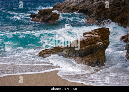 Wellen brechen sich am felsigen Strand Stockfoto