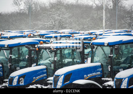 Reihen von Schnee bedeckt, neue Traktoren, bereit für die Lieferung von neuen Holland Traktorenwerk in Basildon, Essex aufgereiht. Stockfoto