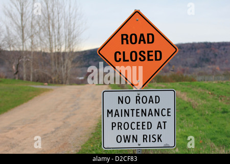 eine Straße Zeichen neben einem Schotterweg und Feld geschlossen, aber das Schild unterhalb es sagt, auf Ihr eigenes Risiko zu gehen, so es ein Paradoxon ist Stockfoto