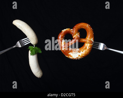 Stilvolle Stillleben mit Weißwurst und Brezel auf zwei Löffeln Stockfoto