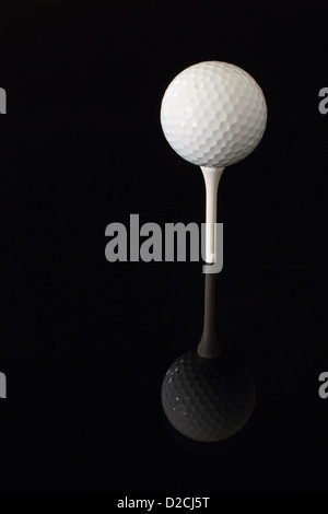 Ein Golfball teed oben auf einem weißen t-Shirt, eine schwarze Oberfläche reflektieren. Stockfoto