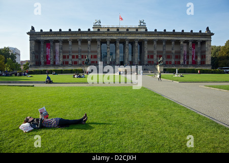 Eine junge Frau entspannt sich und liest in der Lustgarden Berlin, mit dem alten Museum im Hintergrund Stockfoto