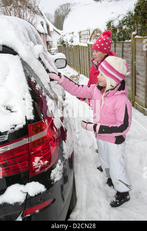 Winter Autofahren mühsam Kinder Schneeräumung von Karosserie und Fenster eines Autos Stockfoto