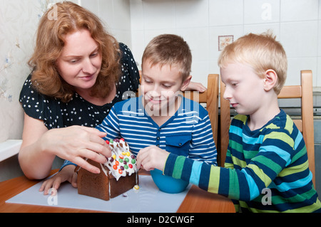 Mutter und zwei Söhne, die Lebkuchenhaus dekorieren Stockfoto