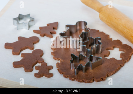 Gebäck-Fräser in Form Lebkuchenmänner, Star und Weihnachtsbaum auf Teig legen Stockfoto