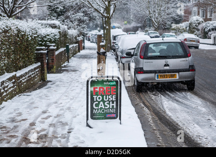 Ein Advertisemnet für ein "frei zu verwenden" Geldautomat im Schnee bedeckt s Straße - Strawberry Hill, Twickenham, Großbritannien Stockfoto