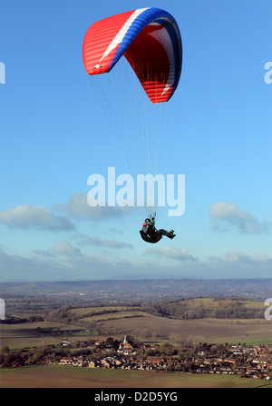 Ein männliche Gleitschirm fliegt über den South Downs in West Sussex mit eine rote Rutsche an einem schönen Tag mit blauem Himmel und weißen Wolken Stockfoto