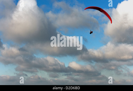 Ein männliche Gleitschirm fliegt über den South Downs in West Sussex mit eine rote Rutsche an einem schönen Tag mit blauem Himmel und weißen Wolken Stockfoto