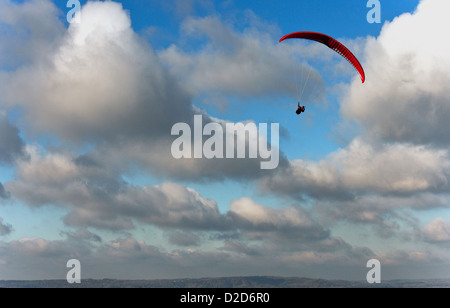 Ein männliche Gleitschirm fliegt über den South Downs in West Sussex mit eine rote Rutsche an einem schönen Tag mit blauem Himmel und weißen Wolken Stockfoto