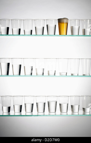 Reihen von Gläsern mit unterschiedlichen Mengen an Wasser und eine mit Bier gefüllt Stockfoto
