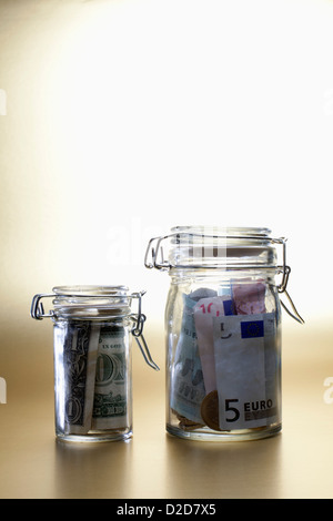 Dollar in einem kleinen Glas neben größeren Glas voller Euro Stockfoto