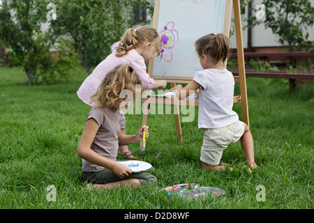 Drei junge Mädchen malen im Hinterhof Stockfoto