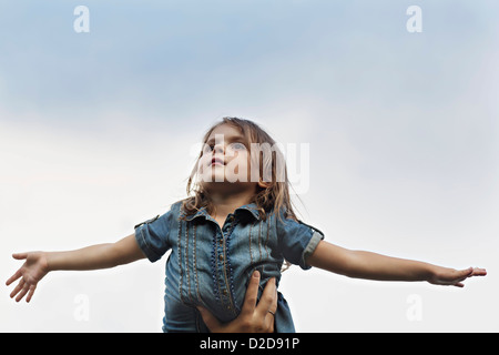 Eine Hand hält ein junges Mädchen, der vorgibt, ein Flugzeug zu sein Stockfoto
