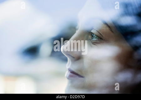 Eine junge Frau schaut nachdenklich aus dem Fenster von einem stationären Auto Stockfoto