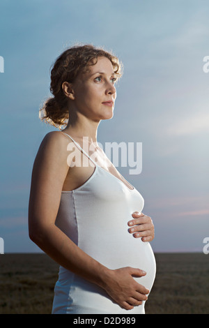 Eine schwangere Frau ihren Bauch halten und nachdenklich wegschauen Stockfoto