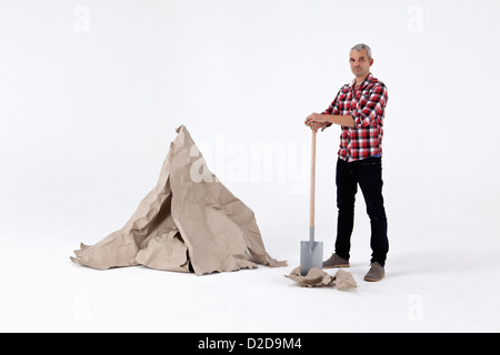 Ein Mann stand von ausgegraben Bastelpapier Felsen, neben einem künstlichen Papier Felsbrocken Stockfoto