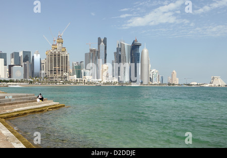 Ein einsamer Fischer versucht sein Glück an der Corniche von Doha in Katar mit dem Großteil der Stadt neue Hochhaus-Skyline hinter Stockfoto