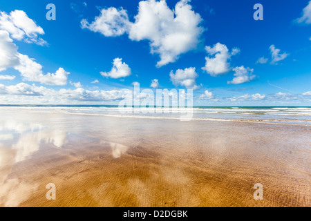 Leerer Strand mit flauschigen Wolken reflektiert im nassen Sand, Saunton Sands in North Devon, UK. Stockfoto