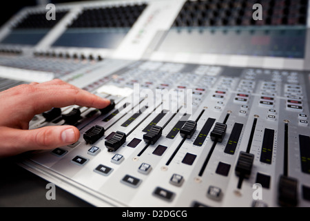 Nahaufnahme einer Hand auf einen Fader auf ein TV-Studio Mischpult. Stockfoto