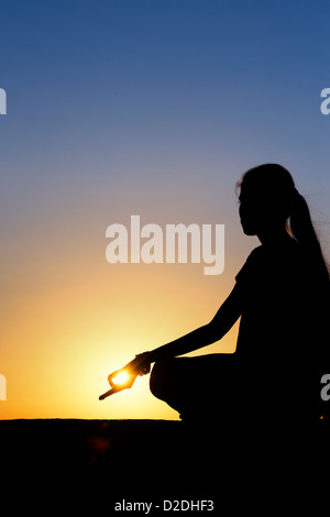 Sonnenuntergang Silhouette eines indischen Mädchen meditieren. Andhra Pradesh, Indien Stockfoto