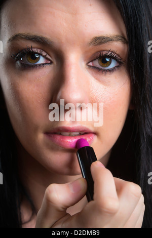 Weibliche Teenager, dunkle Haare, Auftragen von Lippenstift, 18 Jahre, kaukasische Stockfoto