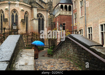 Touristen mit blauen Schirm Spaziergänge im Regen durch die Straßen von Brügge, Belgien Stockfoto