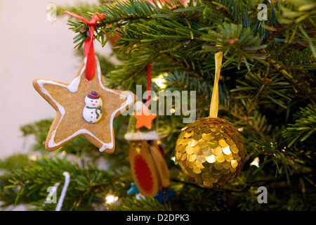 Vintage Stoff und Glas Christbaumschmuck eine Nordmanntanne Weihnachtsbaum hängen. Auch hängt einen essbare Schneemann-Cookie. Stockfoto