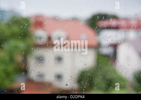 Regentropfen fließen auf Fensterglas nach Hause verschwommen Stockfoto