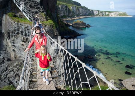 Frau und Kind überqueren Carrick-a-Rede Rope Bridge, County Antrim, Nordirland. Stockfoto